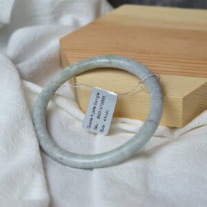 Natural Grade A jadeite jade bangle bracelet in pale green tone, minimalist round design, size 61mm, photographed on wooden display