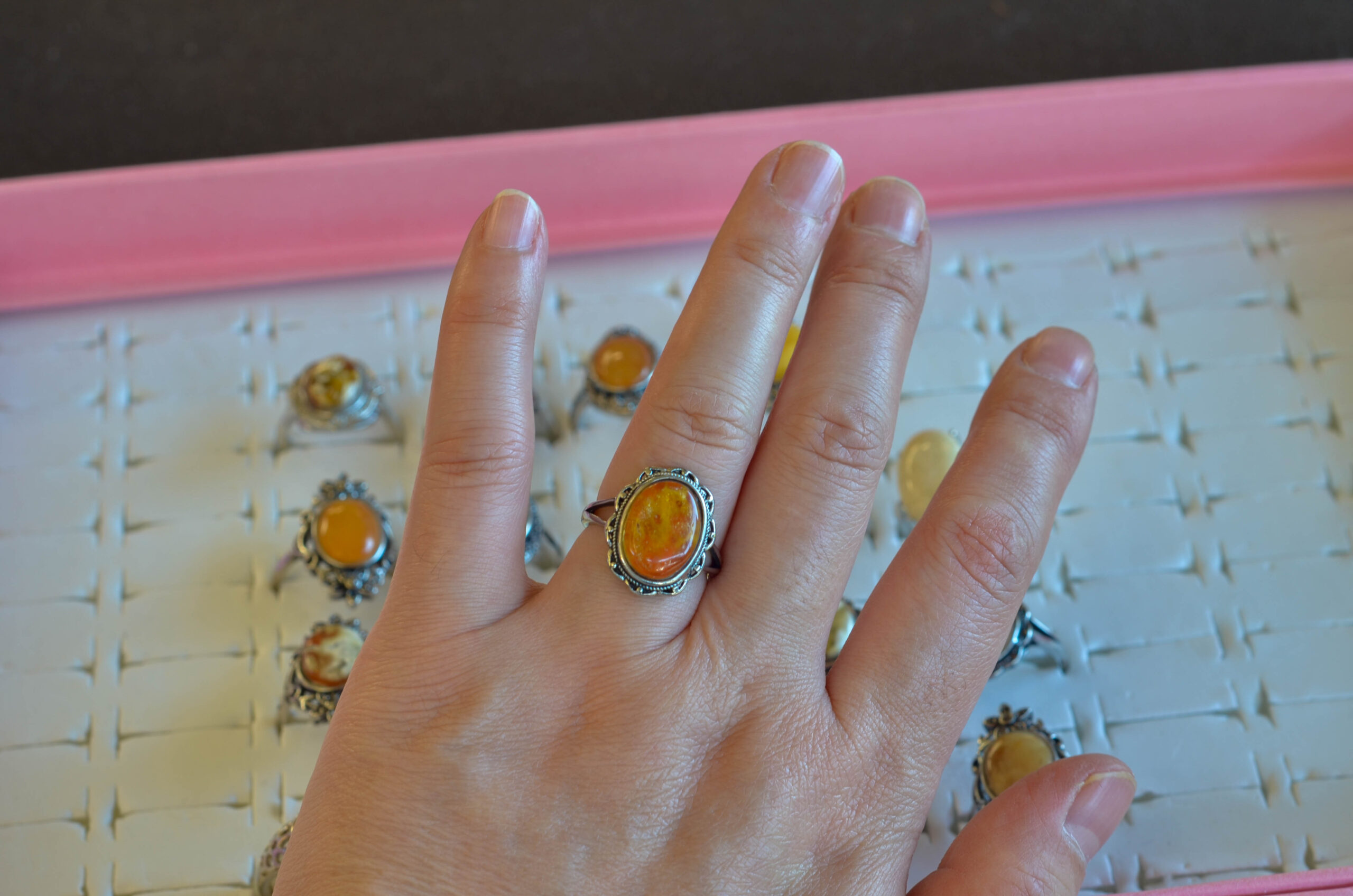 Natural amber ring with an open back, tried on hand